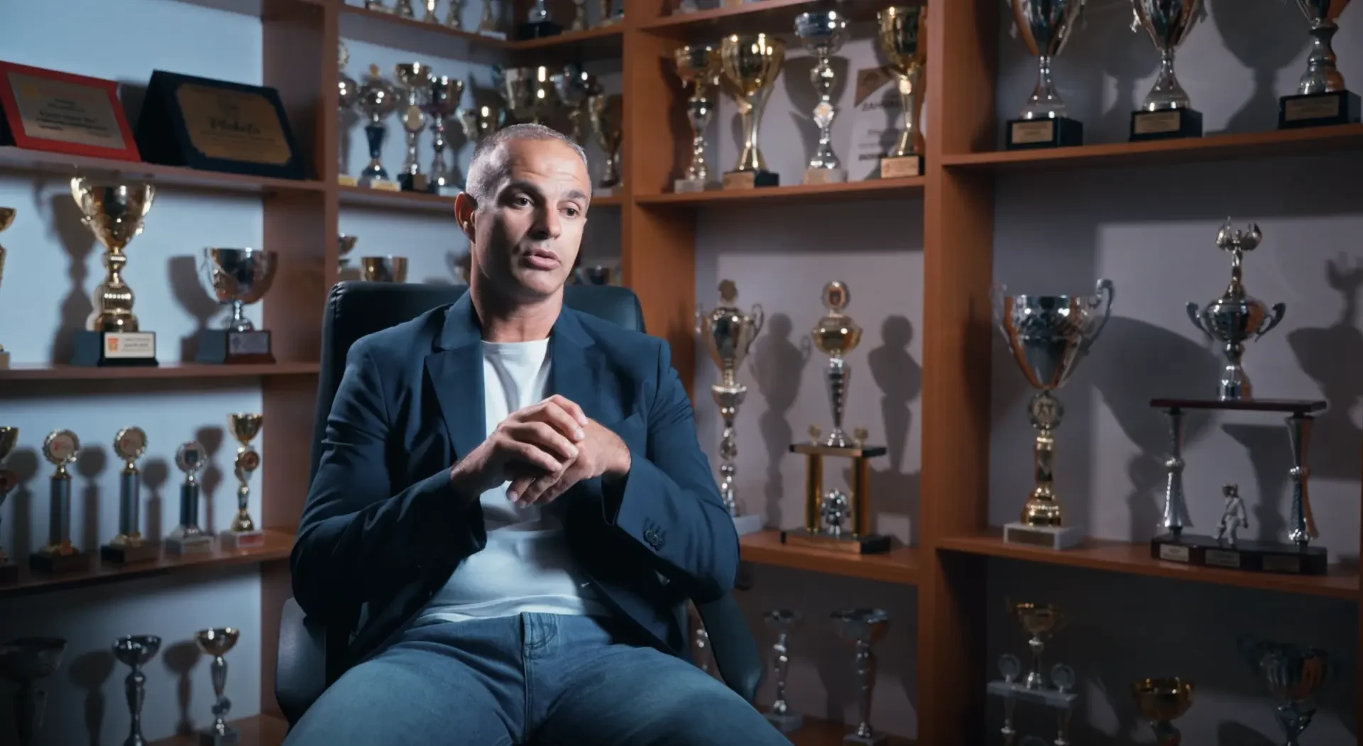 Sagovornik tokom intervjua ispred polica s trofejima.