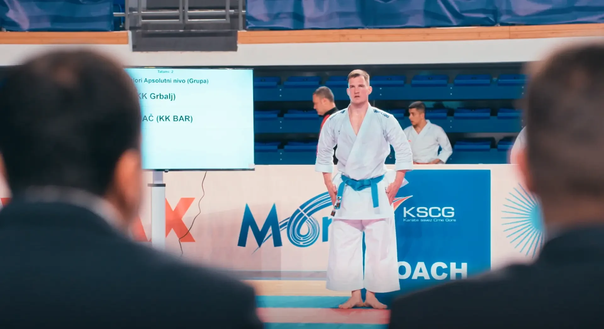 Sportista izvodi katu dok ga sudije posmatraju.